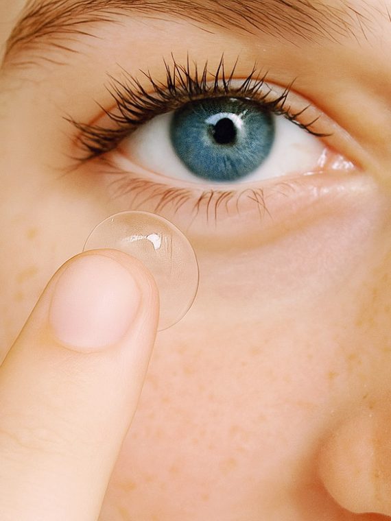 Lady with blue eyes putting in a contact lense